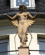 Belle statue d'une femme munie d'une cape au faîte de l'angle arrondi de la façade
