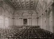 Cette photographie montre sûrement la grande salle du 1er étage, au-dessus de l’entrée, nommée «Aula» sur l’ancien plan [archive], et qui correspond à la salle Pasteur sur le plan actuel [archive].