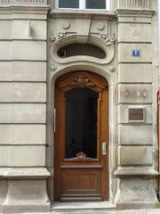 Belle porte d'entrée surmontée d'une baie en forme de gueule béante, le tout dans un style néo-baroque