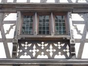 Troisième fenêtre en partant de la gauche, au premier étage sur la façade vers la rue des Moulins.
