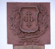 Décor sculpté en grès avec croix et décor végétal symbolique, scellé au-dessus du portail